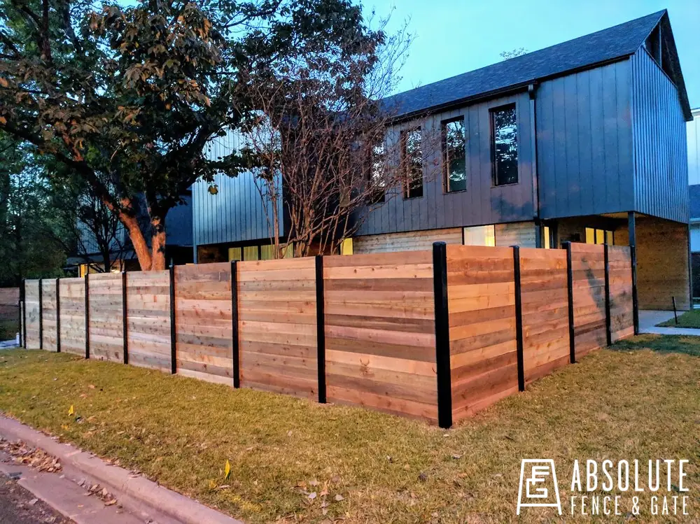 Horizontal cedar fence with black metal posts installed by Absolute Fence & Gate